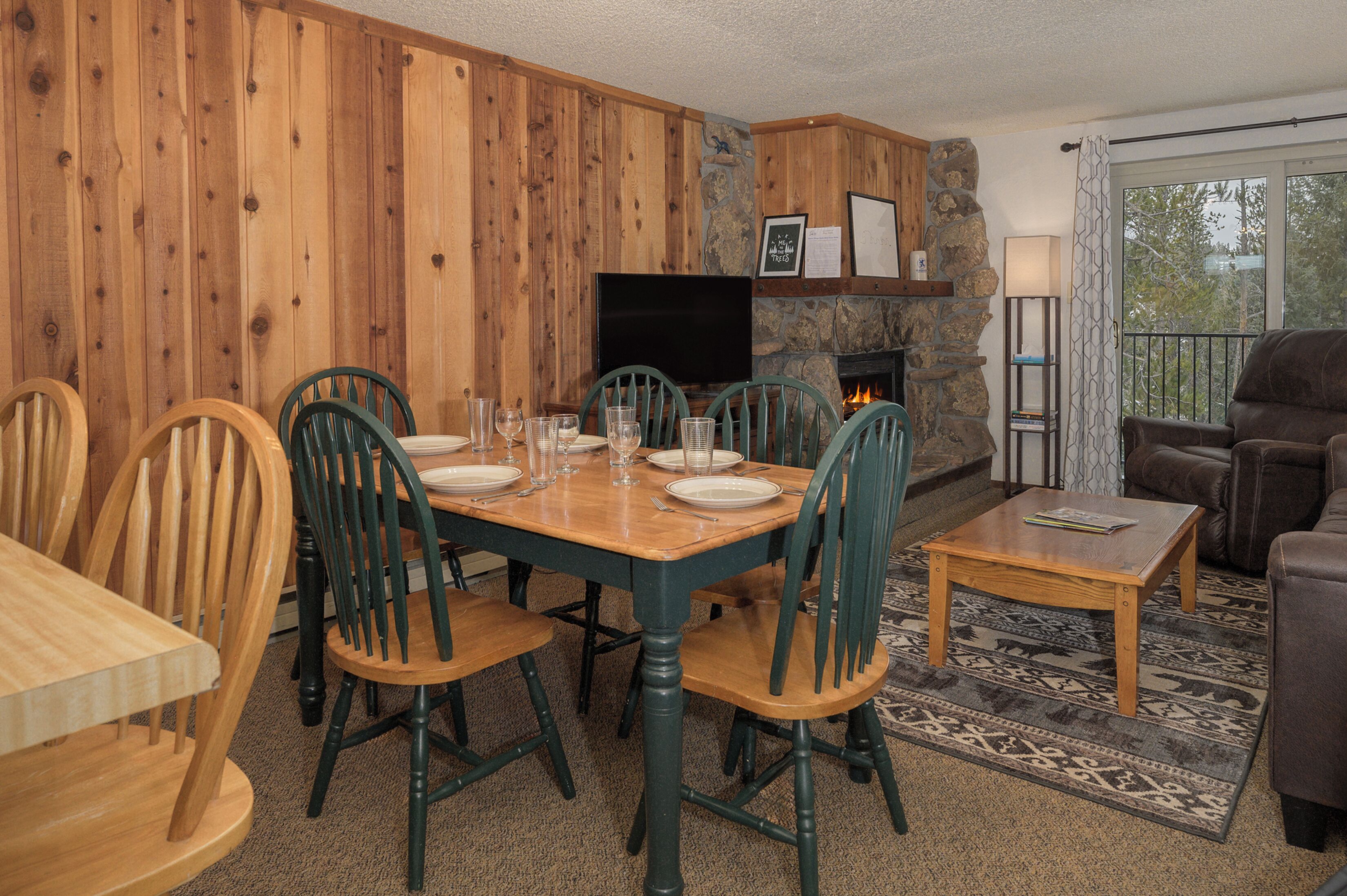 Un coin repas avec une table et des chaises en bois, un téléviseur et une cheminée en pierre.