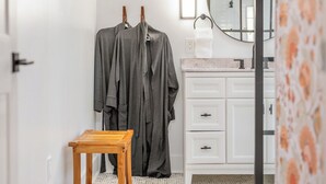 Une salle de bain avec un meuble-lavabo blanc, un miroir et un tabouret en bois.