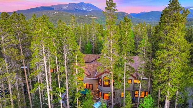 A two-story house surrounded by tall pine trees, with a mountain in the background. - NEW Cedar Lodge on Peak 8 | Private Hot Tub, Firepit, Grill & Easy Shuttle Access (Breckenridge)