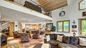A spacious living area with a high ceiling, wooden flooring, and a balcony with a railing. - NEW Cedar Lodge on Peak 8 | Private Hot Tub, Firepit, Grill & Easy Shuttle Access (Breckenridge)
