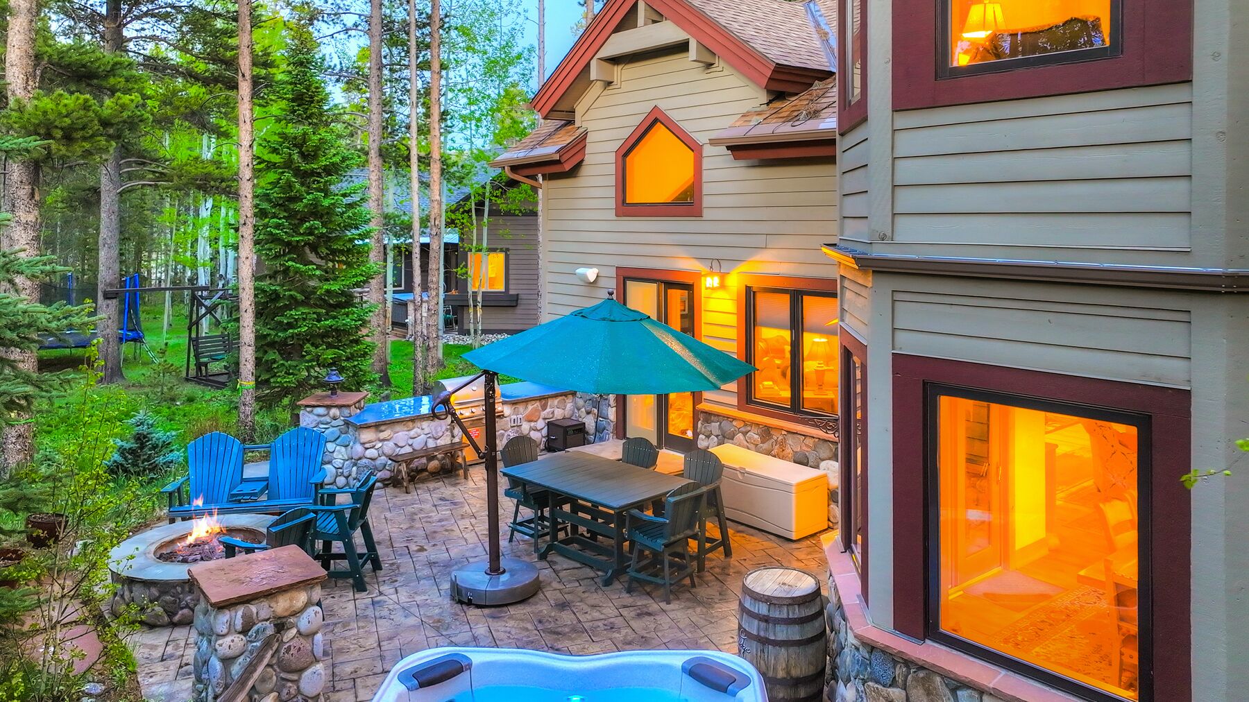 Eine gemütliche Terrasse mit Feuerstelle aus Stein, einem Tisch und Stühlen sowie einem Whirlpool.