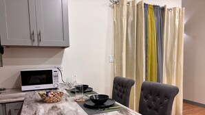 Una cocina con microondas, un tazón, un vaso y una cesta de bocadillos sobre la encimera.