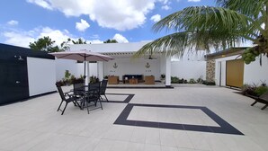 A patio area with a dining table and chairs, a sofa, and a ceiling fan.