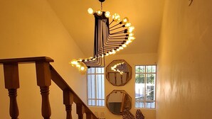 A staircase with wooden balusters, a modern light fixture, and decorative mirrors.