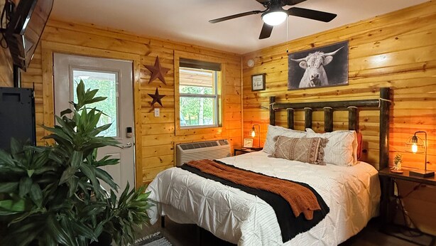 Un dormitorio rústico de madera con cama, ventilador de techo y decoración con estrellas en la pared.