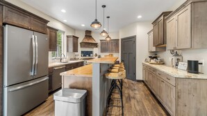 A modern kitchen with stainless steel appliances, wooden cabinets, and a central island with bar stools.
