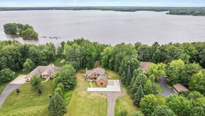A residential area with houses surrounded by lush greenery and a large body of water in the background.