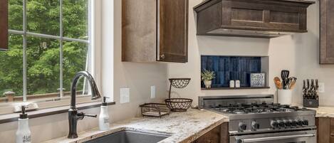 A kitchen with a double sink, stainless steel stove, and wooden cabinets.