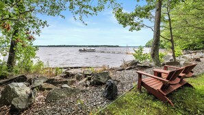 A lakeside view with a wooden deck and Adirondack chairs overlooking the water.