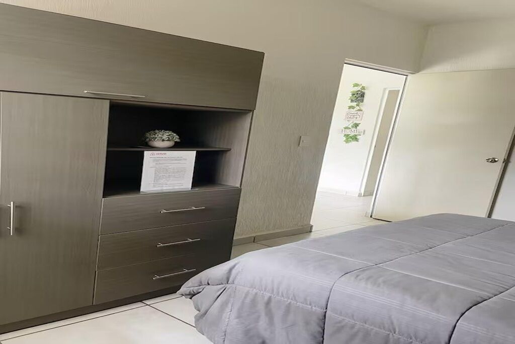 Et soveværelse med seng, garderobe og dør.