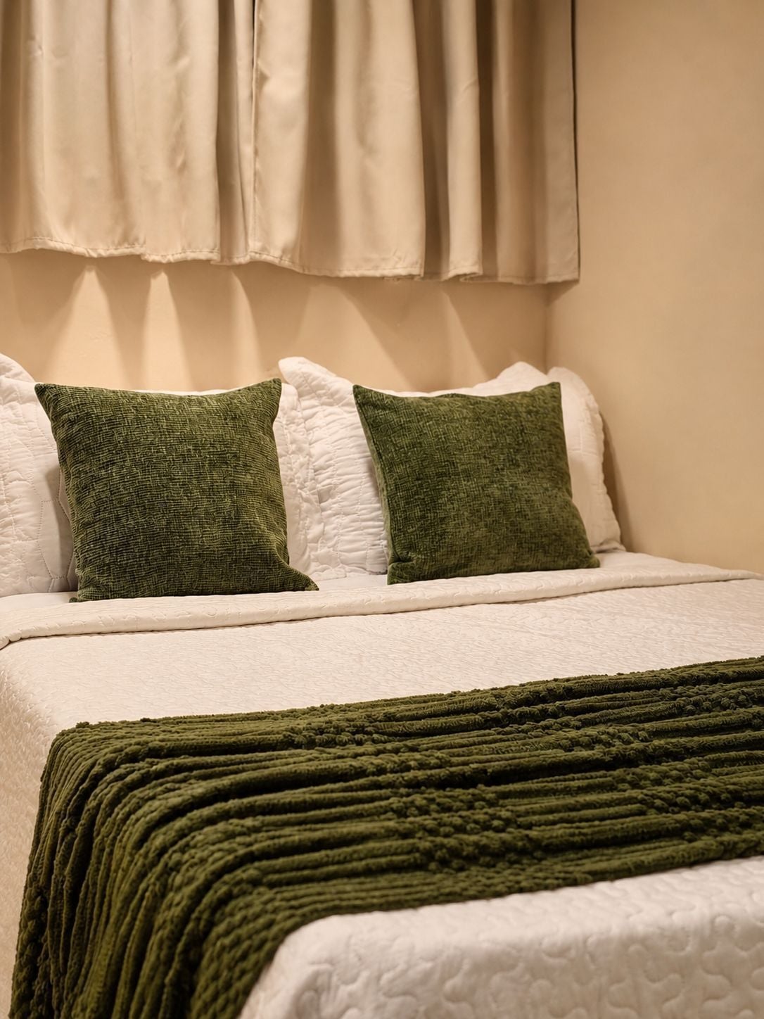Ein Bett mit weißer Bettwäsche und zwei grünen Kissen.