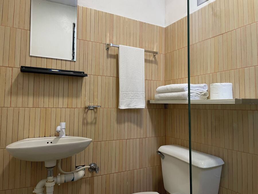 A bathroom with a sink, toilet, towel rack, and a shelf with towels.