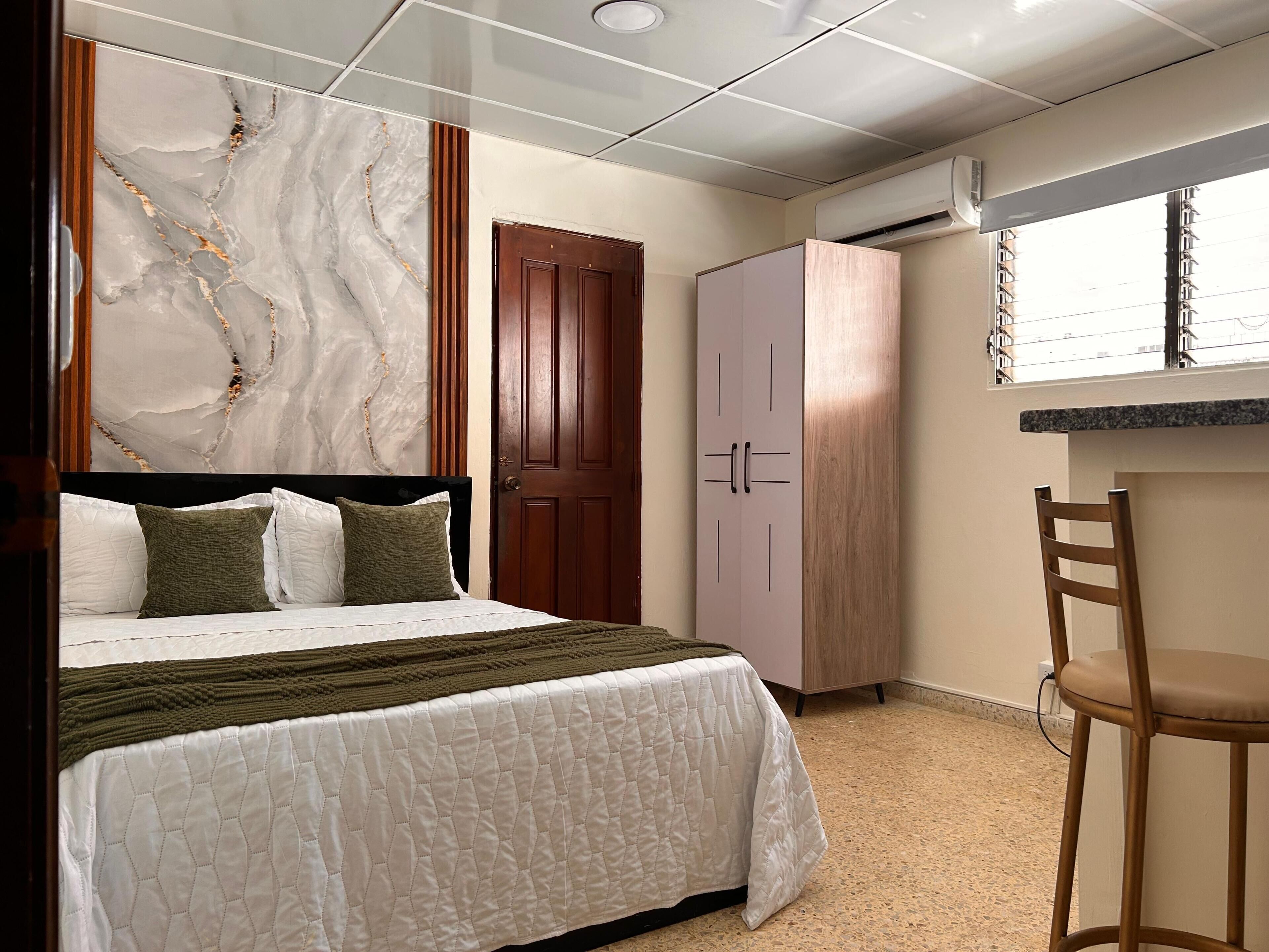 Une chambre d’hôtel avec un lit, une armoire, un bureau et une chaise.