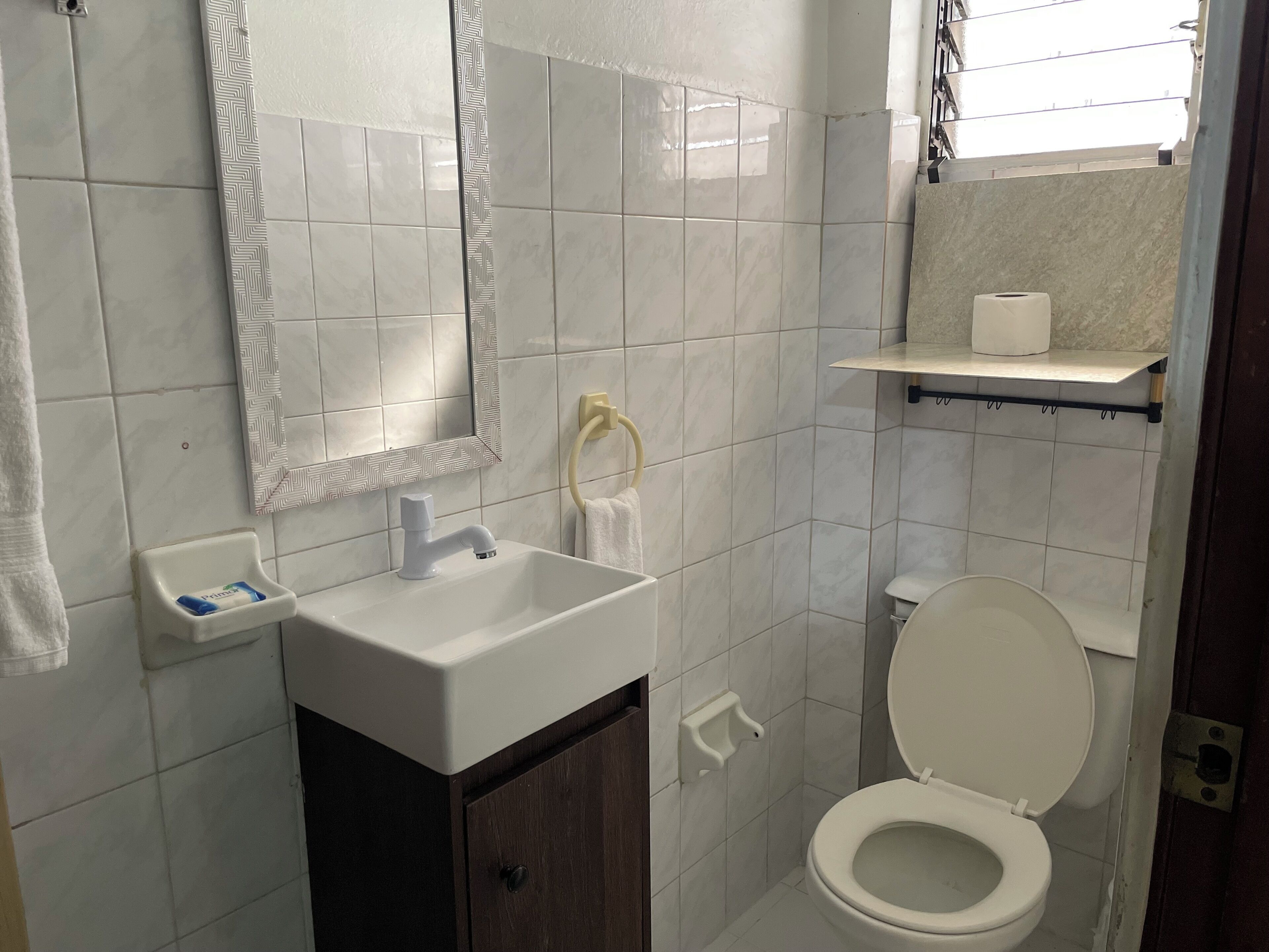 Une salle de bain avec un lavabo blanc, un miroir, des toilettes et un porte-serviettes.