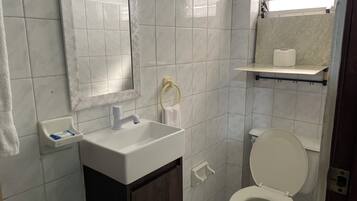 Une salle de bain avec un lavabo blanc, un miroir, des toilettes et un porte-serviettes.