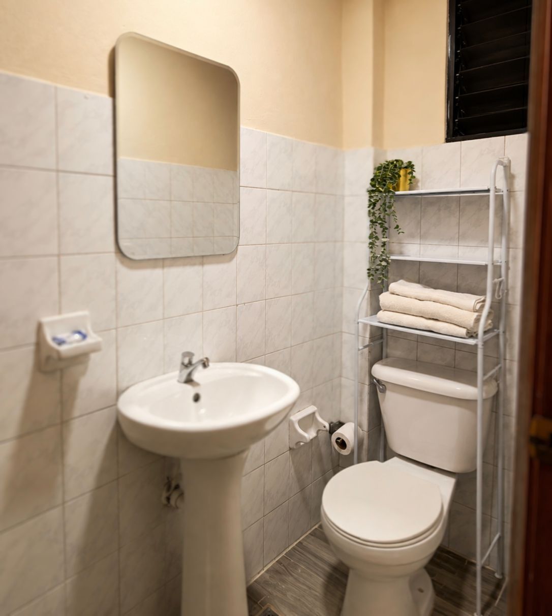 Une salle de bain avec un lavabo sur colonne, des toilettes et un porte-serviettes avec des serviettes pliées.