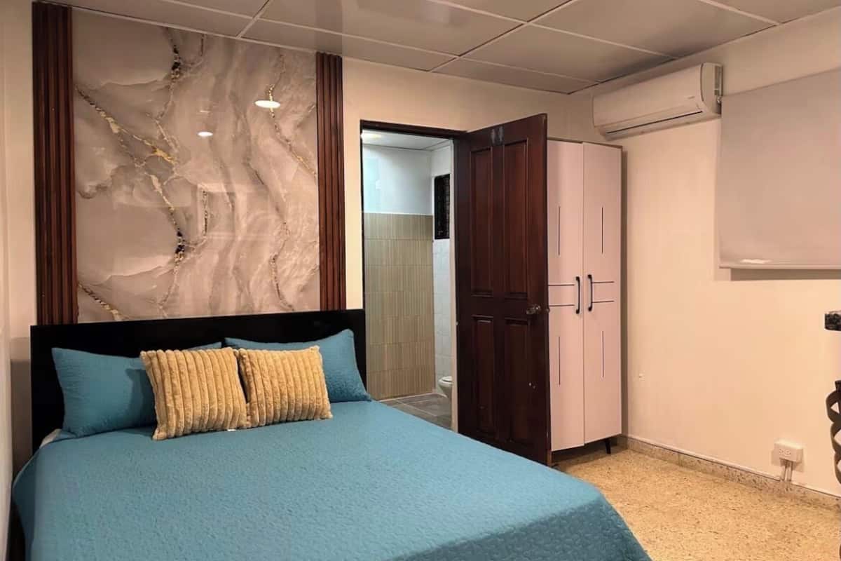 A bedroom with a bed, a wardrobe, and a marble wall.