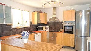 Una cocina moderna con armarios de madera, electrodomésticos de acero inoxidable y una isla central.