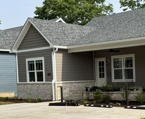 A two-story house with a grey roof, white trim, and a stone foundation.