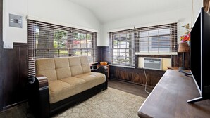 Una habitación con sofá, televisión y ventana con persianas.