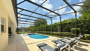 A covered outdoor swimming pool with lounge chairs and a small hot tub. - Resort Villa! Pool, Hot Tub & Game Room by Disney! (Kissimmee)
