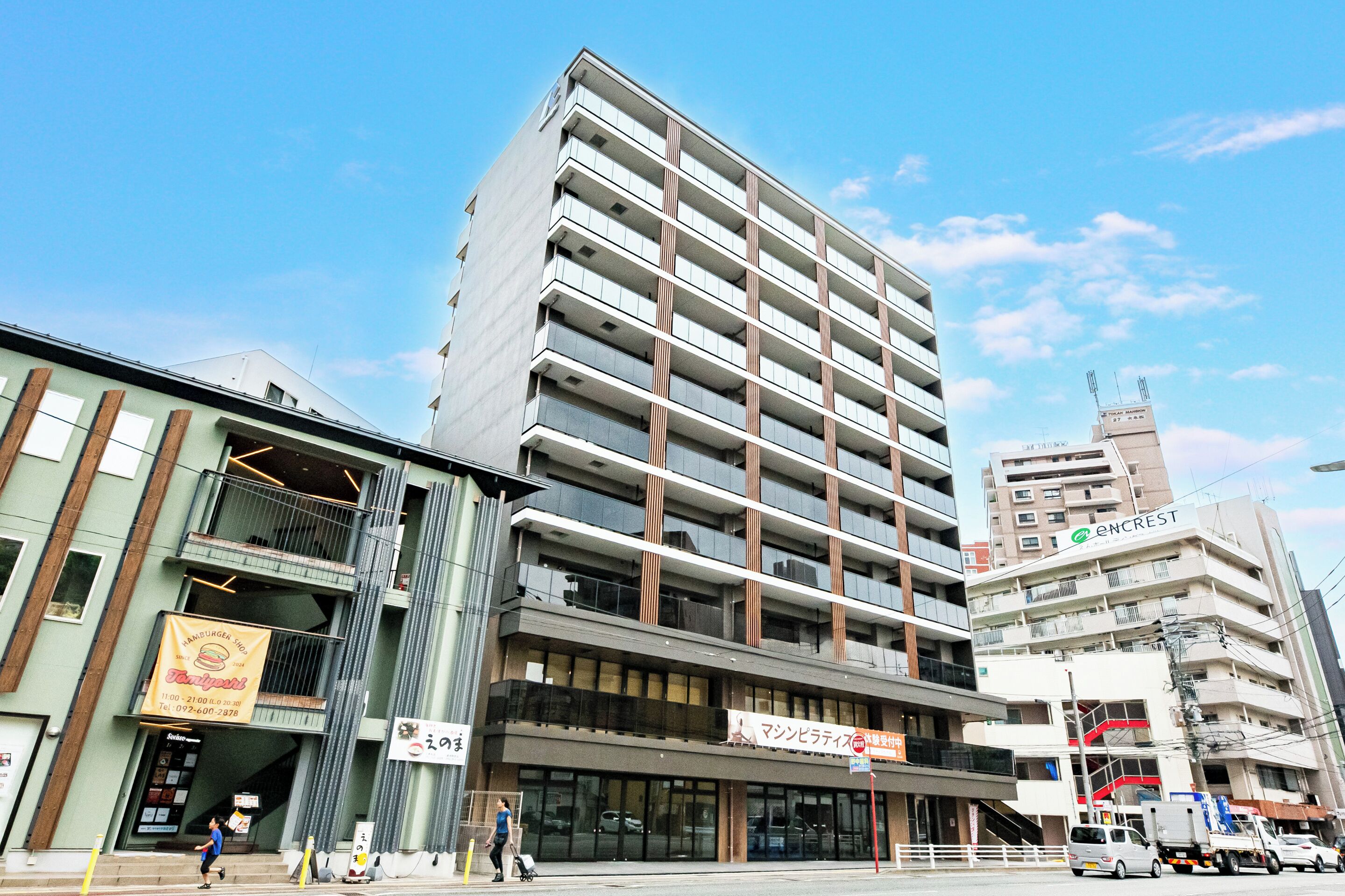 A multi-story building with a modern design, featuring balconies and a prominent ENCREST sign.