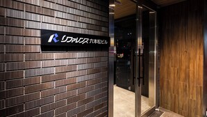 A modern building entrance with a dark brick facade and a glass door leading inside. - Hotel Reference Ropponmatsu Condominium (Fukuoka)