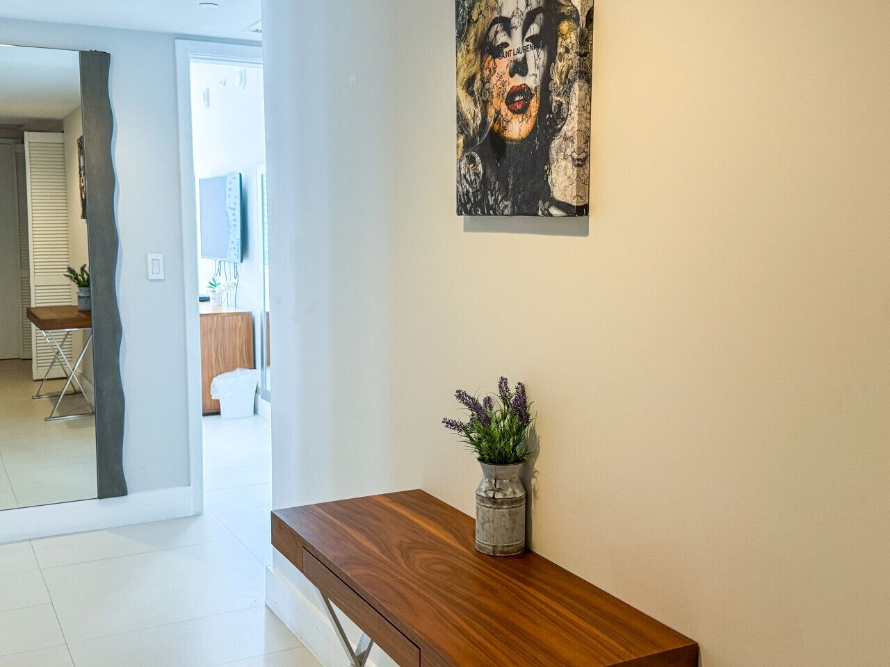 A modern interior with a wooden bench, a vase with plants, and a wall-mounted artwork.