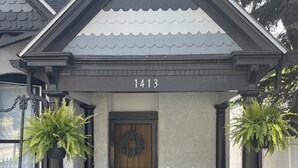 Una casa con el número 1413, una puerta principal, dos mecedoras blancas y una corona en la puerta.