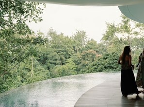 A wooden deck overlooking a body of water with dense greenery in the background.