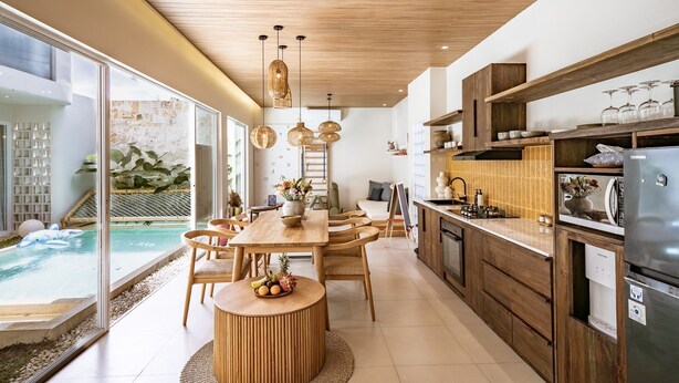 A modern kitchen with wooden cabinets, a built-in oven, and a large island with seating.