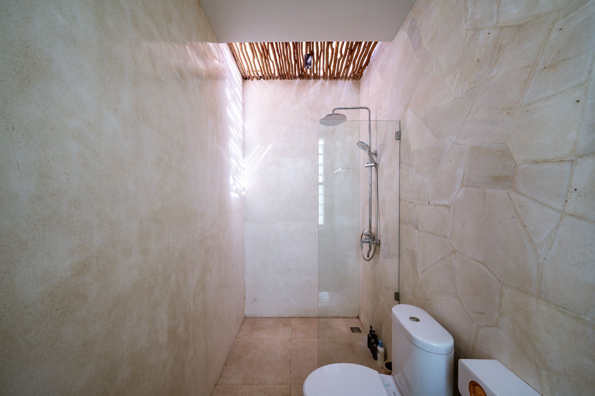 Un baño con cabina de ducha de vidrio, inodoro y lavamanos.