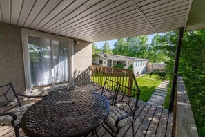 A covered patio with a round table and chairs, a sliding glass door, and a view of a house and yard.