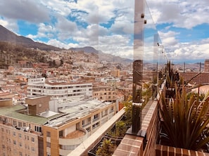 A high-rise building with a rooftop garden and a view of a cityscape with mountains in the background.