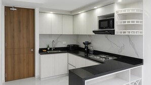 A modern kitchen with white cabinets, a black countertop, and a built-in microwave.