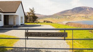 Ein Cottage namens 'Kilmartin Cottage' mit einem Schotterweg, der zu einem weißen Gebäude mit einem Ziegeldach führt.