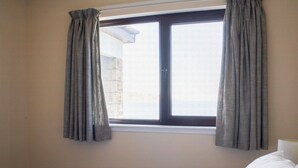 Ein Hotelzimmer mit Bett, einem Fenster mit Vorhängen und Blick nach außen.