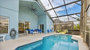 Uma área de piscina com ventilador de teto, cadeiras azuis e banheira de hidromassagem.