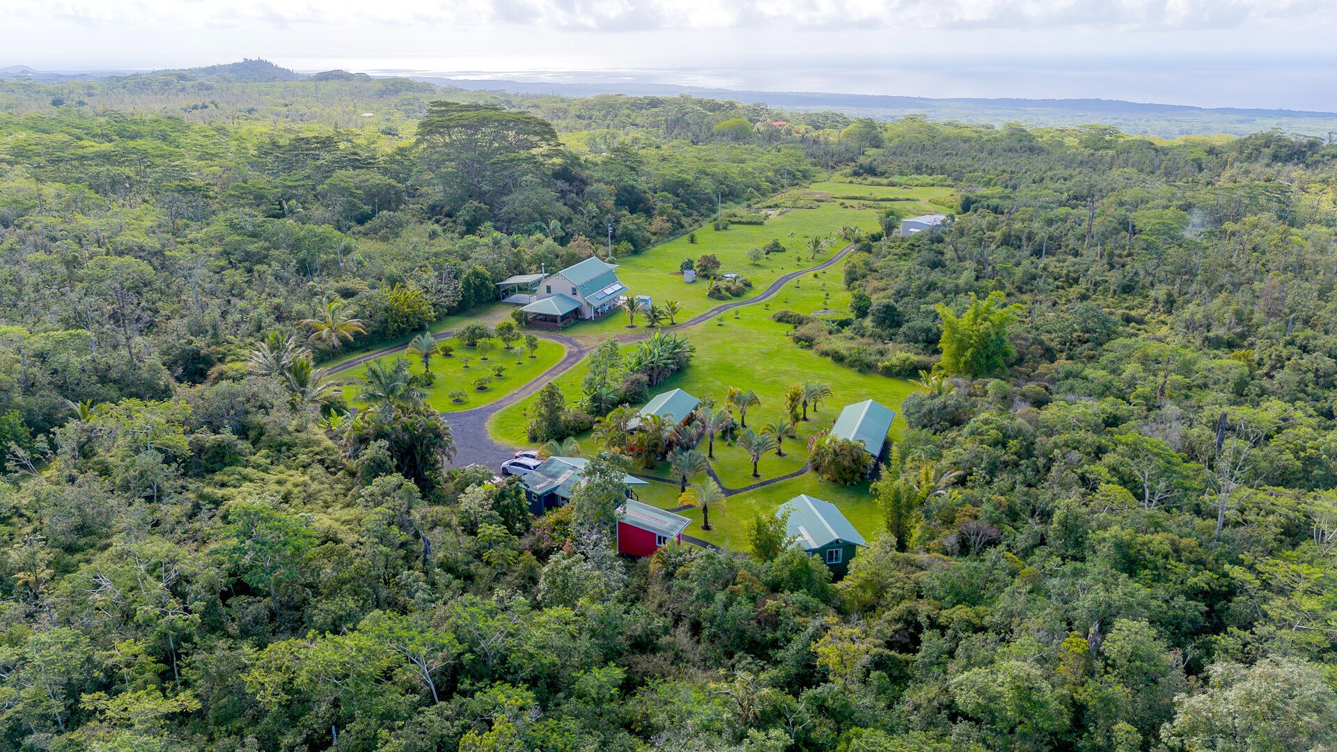 An aerial view of a resort with multiple buildings, surrounded by dense forest.