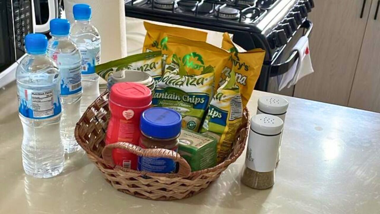 A kitchen counter with a basket containing Mountain Chips, water bottles, a red container, a blue container, and salt and pepper shakers.
