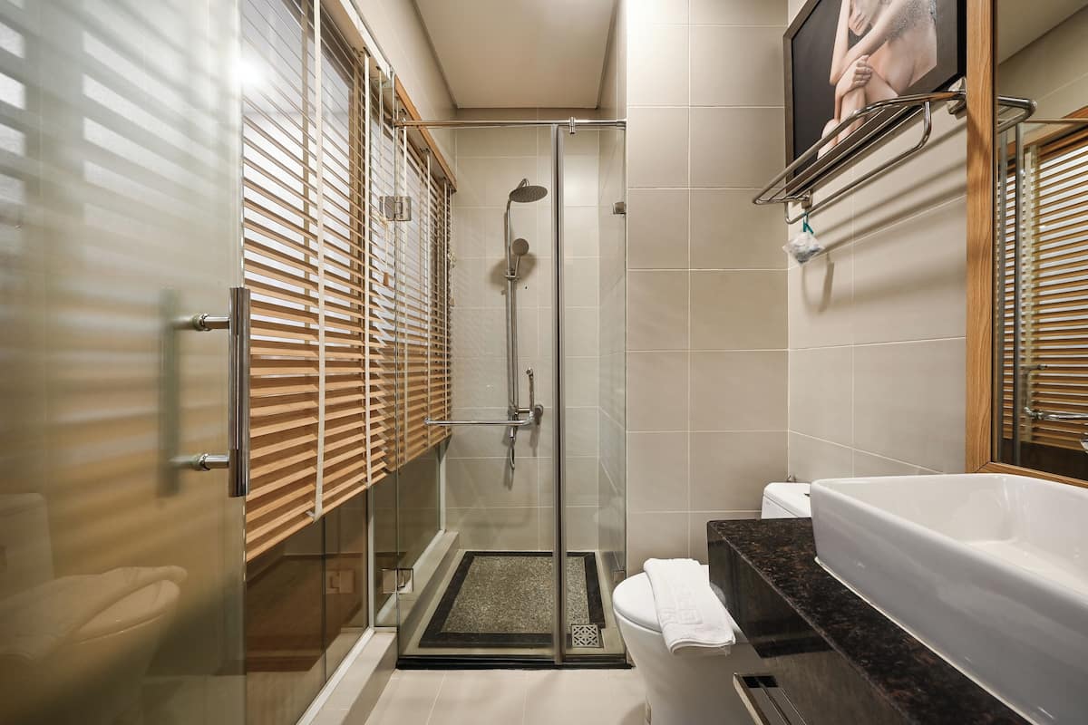 Un baño moderno con ducha de vidrio, una bañera blanca y persianas de madera.