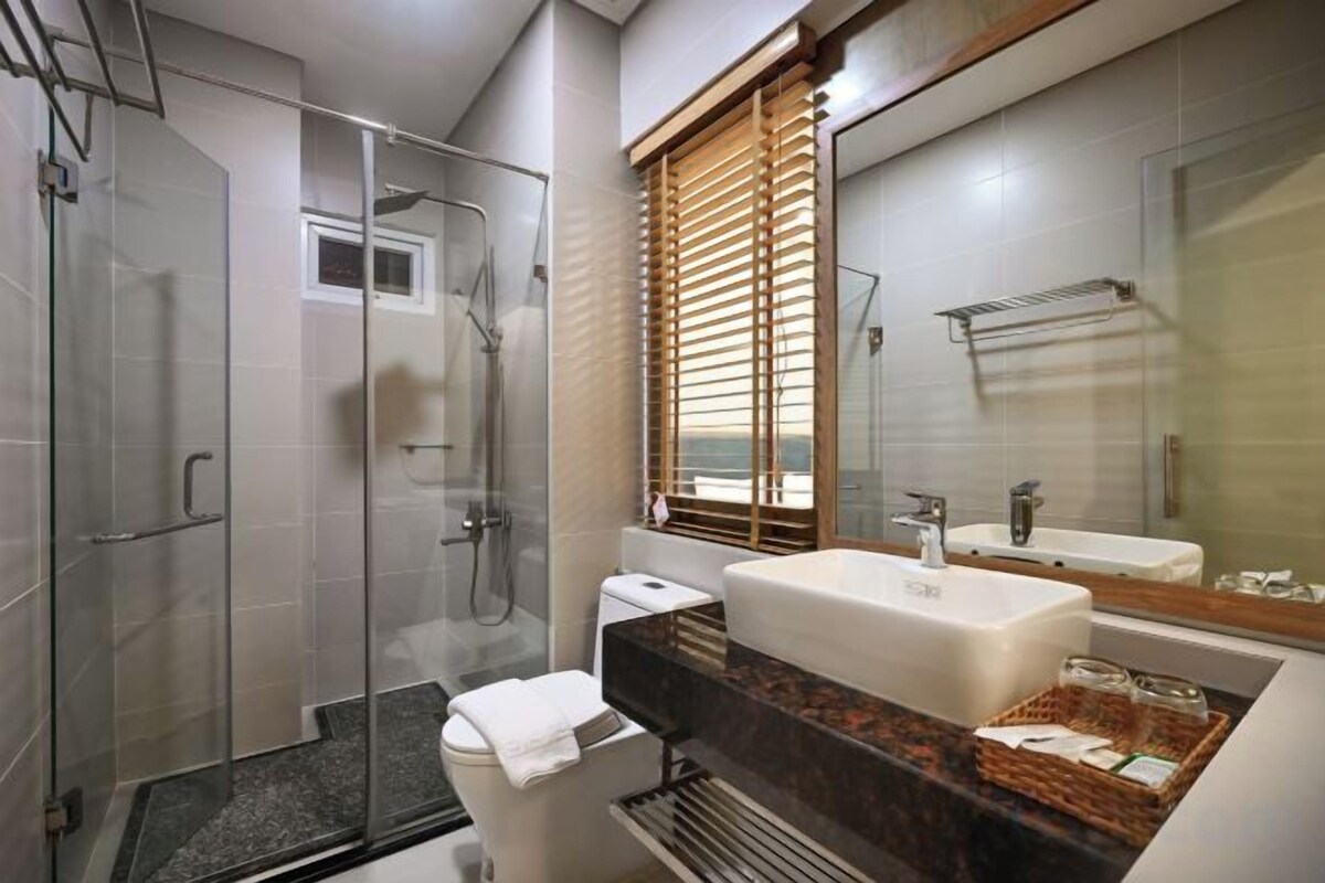 Une salle de bain moderne avec une douche à parois de verre, des toilettes, un lavabo et un grand miroir.