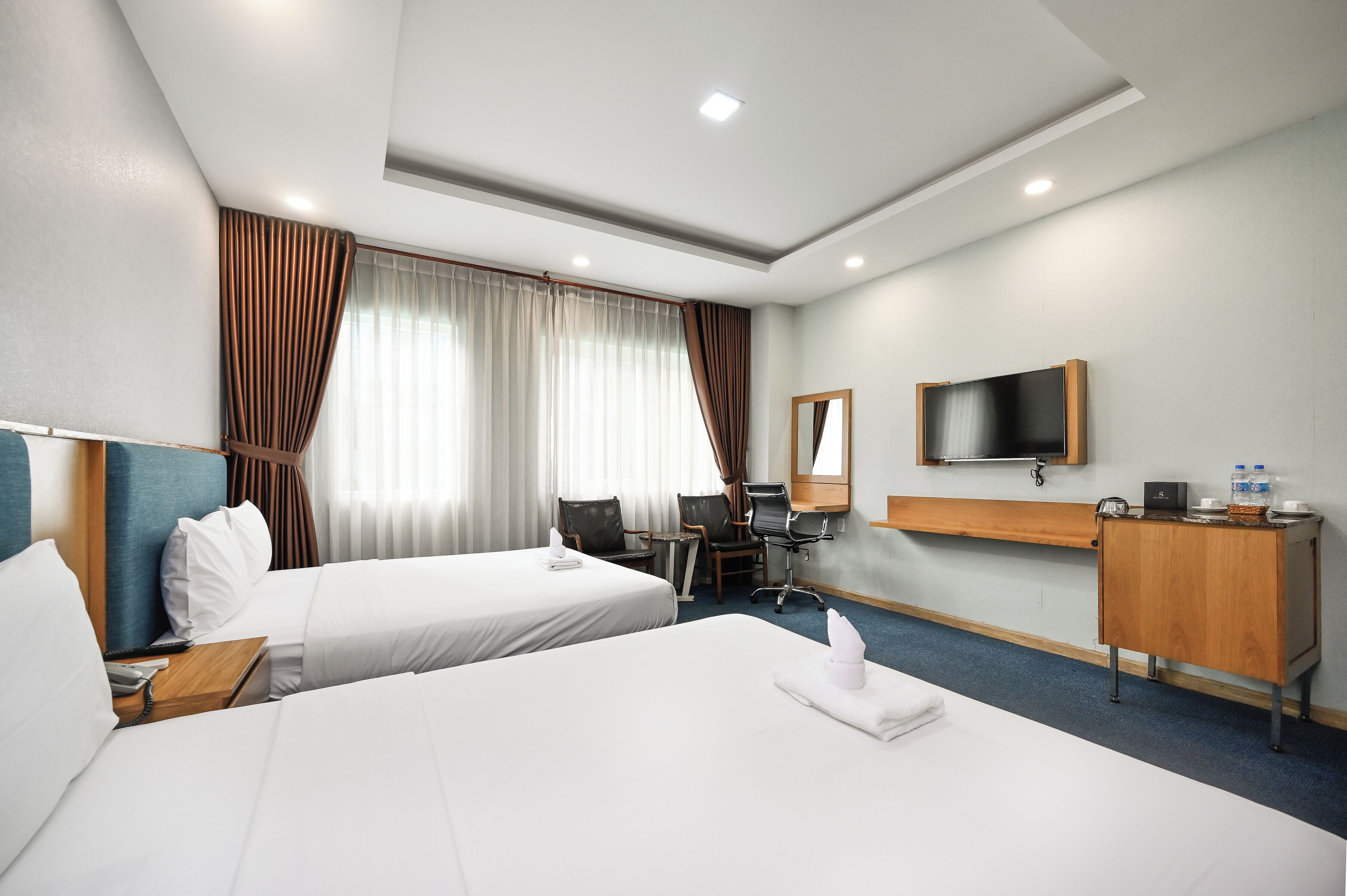 Une chambre d’hôtel avec deux lits, un bureau, une chaise, une télévision et un mini-bar.