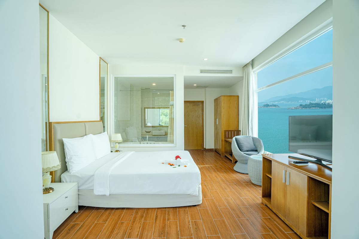 Habitació d'hotel amb llit, televisió, escriptori i vista al mar.