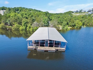 Un edificio grande de una sola planta con techo plano, ubicado en un lago rodeado de vegetación densa.