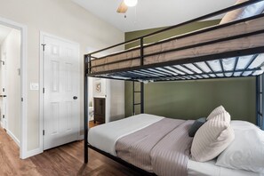 Ein Etagenbett mit Dachfenster, weißen Wänden, Holzboden und einer Tür mit Lichtschalter.