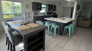 Una cucina moderna con mobili scuri, un'isola centrale e un'area pranzo con tavolo e sedie.