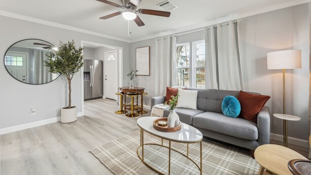 A living room with a ceiling fan, a grey sofa, a coffee table, a side table, and a lamp.