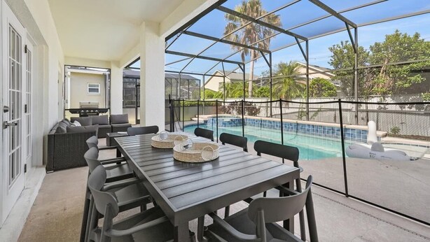 A covered outdoor area with a pool, dining table, and chairs. - Modern Villa w/ Pool, Hot Tub & Theater Room! (Kissimmee)