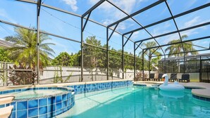An outdoor swimming pool with a glass enclosure, surrounded by palm trees and a white fence. - Modern Villa w/ Pool, Hot Tub & Theater Room! (Kissimmee)